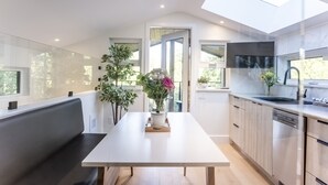 A modern kitchen with a skylight, a dining table with a vase of flowers, and a bench. - Sitka Cabin-Modern, Hikes, OD shower, Pet (Ucluelet)