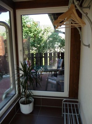 A room with a large window, a potted plant, a metal radiator, and a wooden hanger.