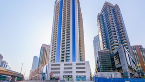 A modern high-rise building with a prominent blue and white facade, surrounded by other tall buildings and a construction site. - Tanin - Spacious Studio Close to Burj Khalifa & Dubai Mall (Dubai)