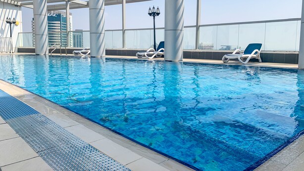 An indoor swimming pool with clear blue water, white lounge chairs, and a modern architectural design. - Tanin - Spacious Studio Close to Burj Khalifa & Dubai Mall (Dubai)