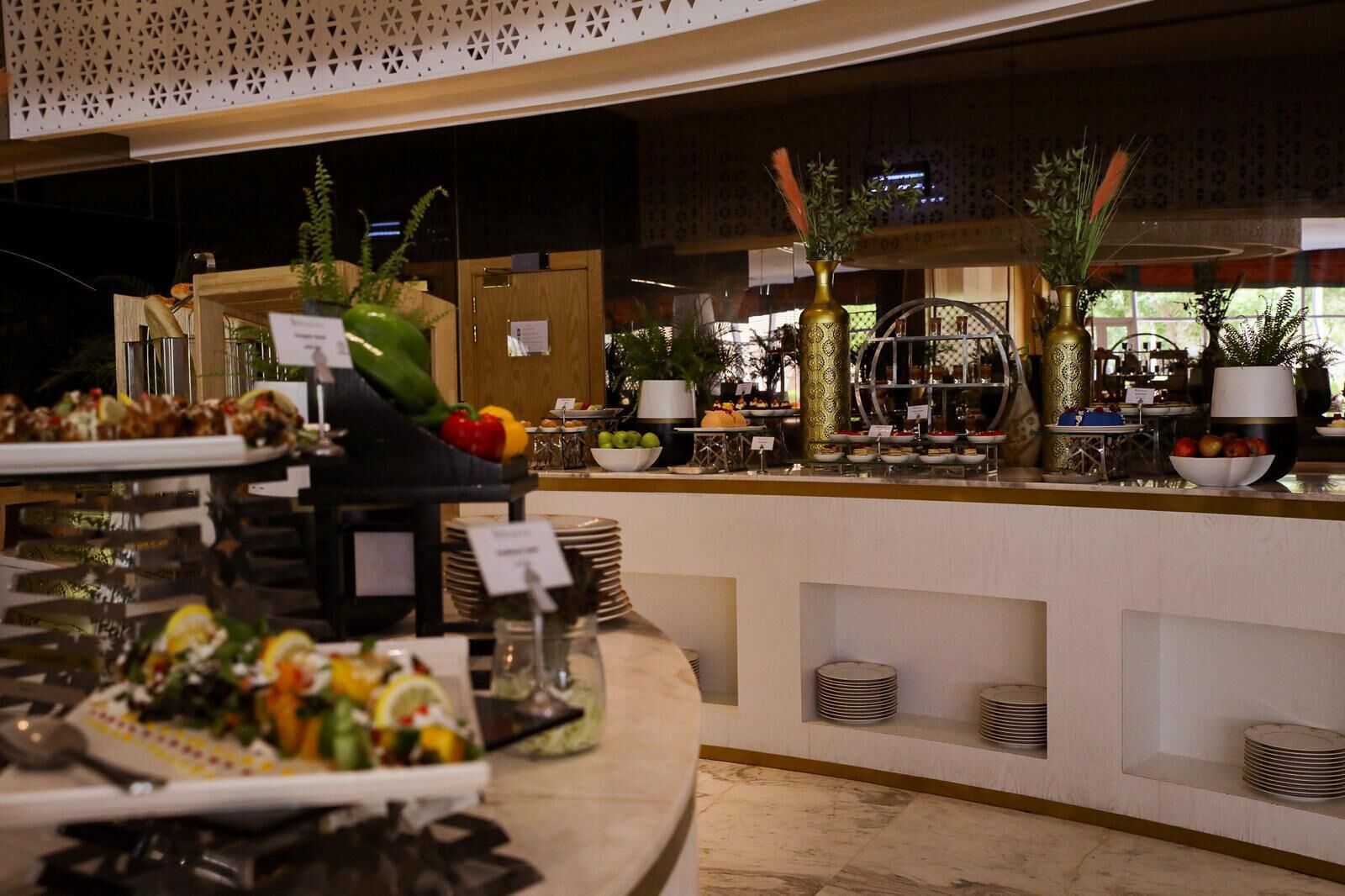 Zona de buffet con diversos alimentos y una recepción al fondo.