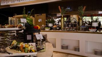 Zona de buffet con diversos alimentos y una recepción al fondo.