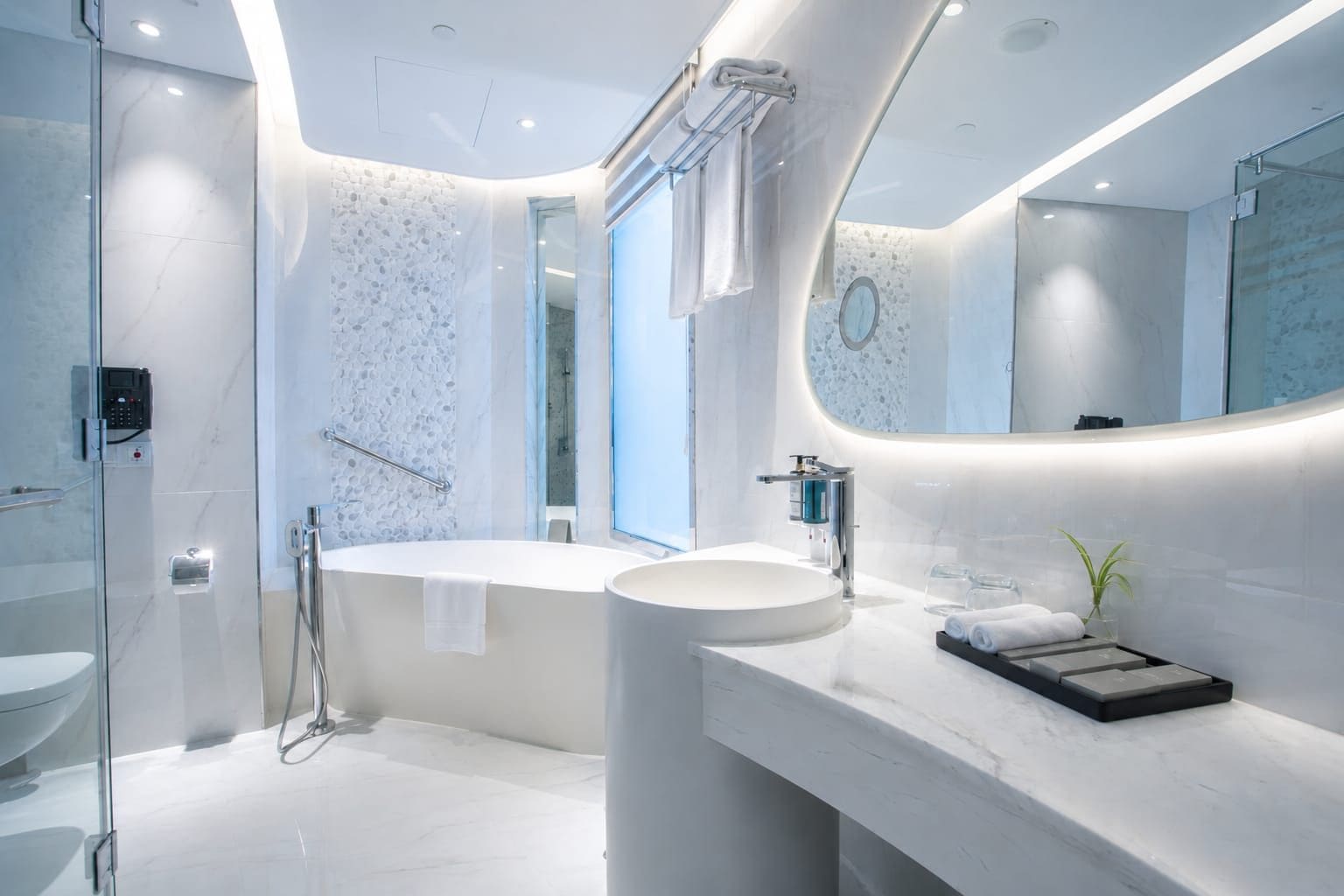 A modern bathroom with a freestanding bathtub, a round sink, and a glass shower enclosure.