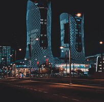 Un edificio moderno con un diseño geométrico distintivo, que presenta dos torres altas y curvas con fachada de celosía.