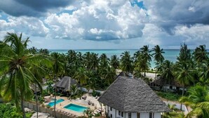 A resort with a swimming pool, palm trees, and a view of the ocean. - Tamu Tamu Boutique Hotel (Pwani Mchangani)
