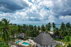 Un resort con piscina, palmeras y vista al océano.