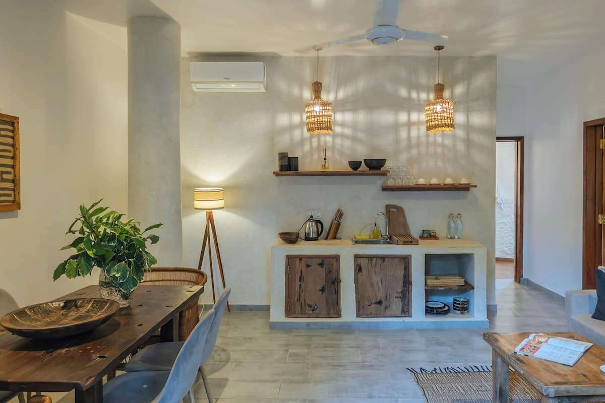 Una cocina moderna con horno integrado, una zona de comedor con mesa y sillas de madera y un ventilador de techo.