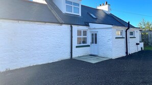 A white two-story house with a grey roof, a small front porch, and a visible chimney. - Beautiful 5BR Rural Cottage with Outstanding Views - Pass the Keys (Castle Douglas)