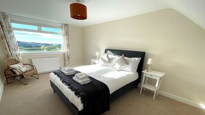 A bedroom with a bed, two bedside tables, a chair, a window with curtains, and a view of the outdoors. - Beautiful 5BR Rural Cottage with Outstanding Views - Pass the Keys (Castle Douglas)