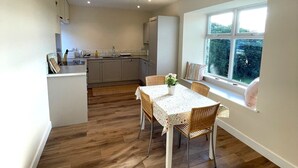 A modern kitchen with a dining area, wooden flooring, and a window with a view of greenery. - Beautiful 5BR Rural Cottage with Outstanding Views - Pass the Keys (Castle Douglas)
