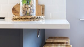 Eine Küchenarbeitsplatte mit einem Glasbehälter voller Korken, einem gewebten Untersetzer und einem Holzschneidebrett.