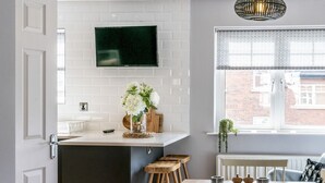 Eine moderne Küche mit Flachbildfernseher, einer kleinen Kochinsel und einem Essbereich mit Tisch und Stühlen.