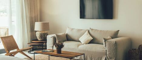 A modern living room with a sofa, a coffee table, a lamp, and a television mounted on the wall.