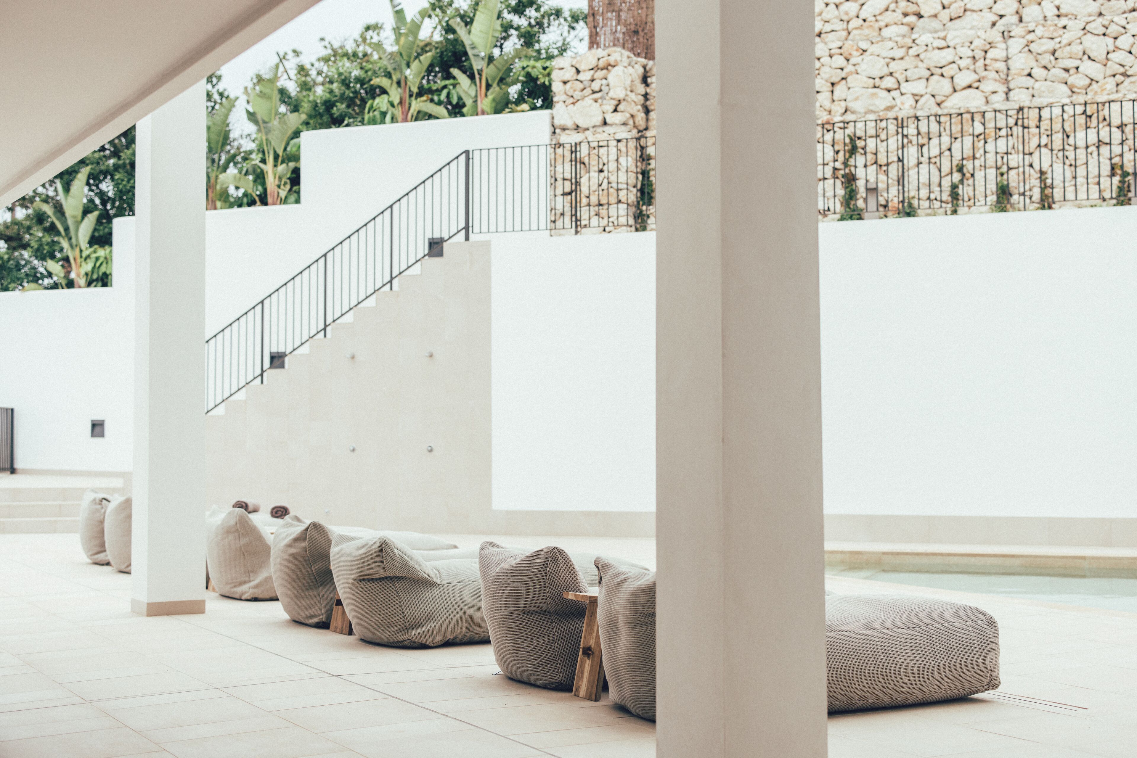 Un interior moderno con una escalera, una piscina y mobiliario exterior.