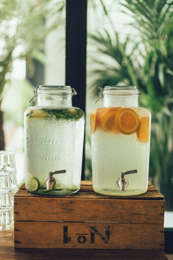 Dos botellas de vidrio con hielo y rodajas de cítricos, sobre una caja de madera con las letras "LON" a la vista.