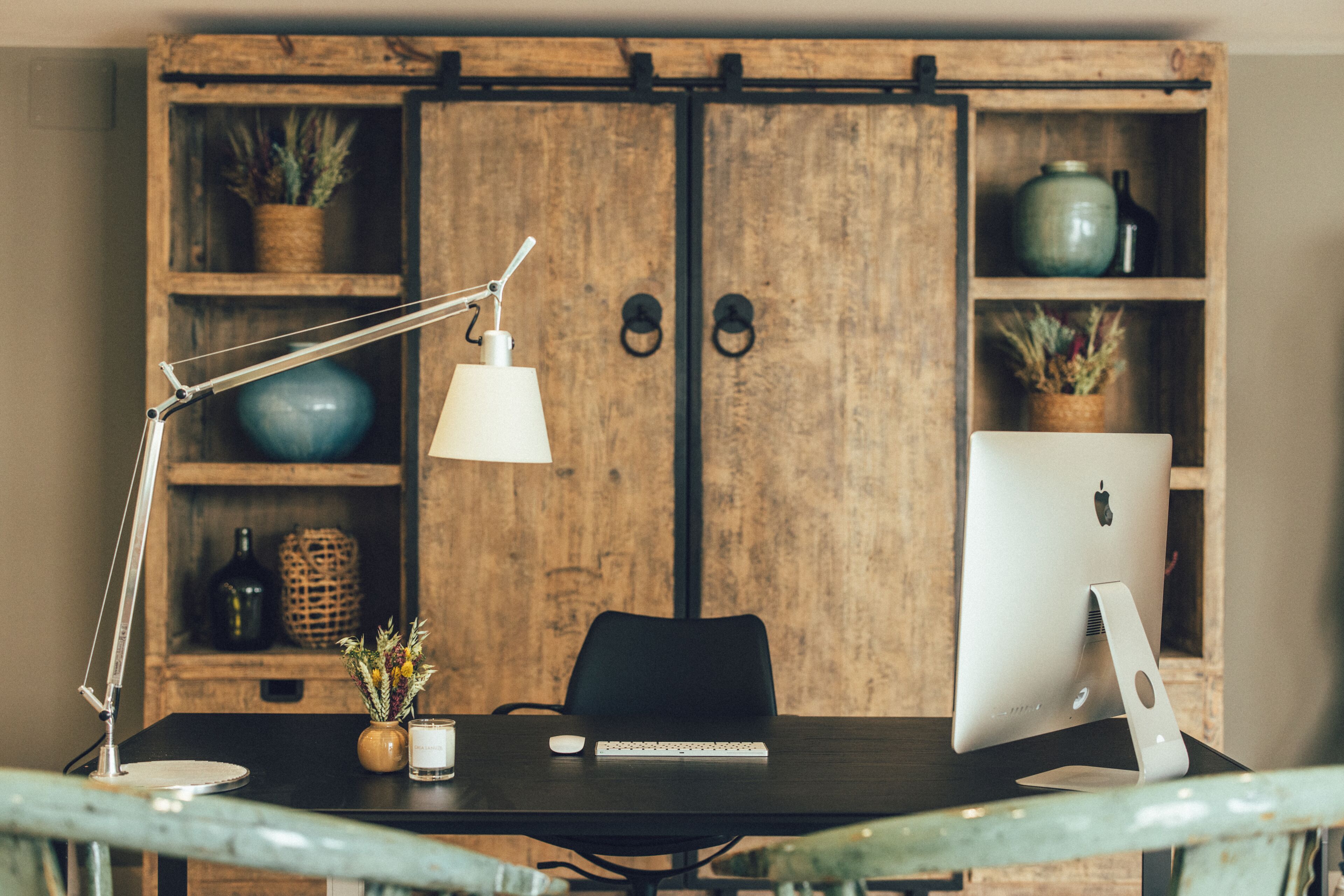A wooden desk with a laptop, a lamp, and a potted plant.