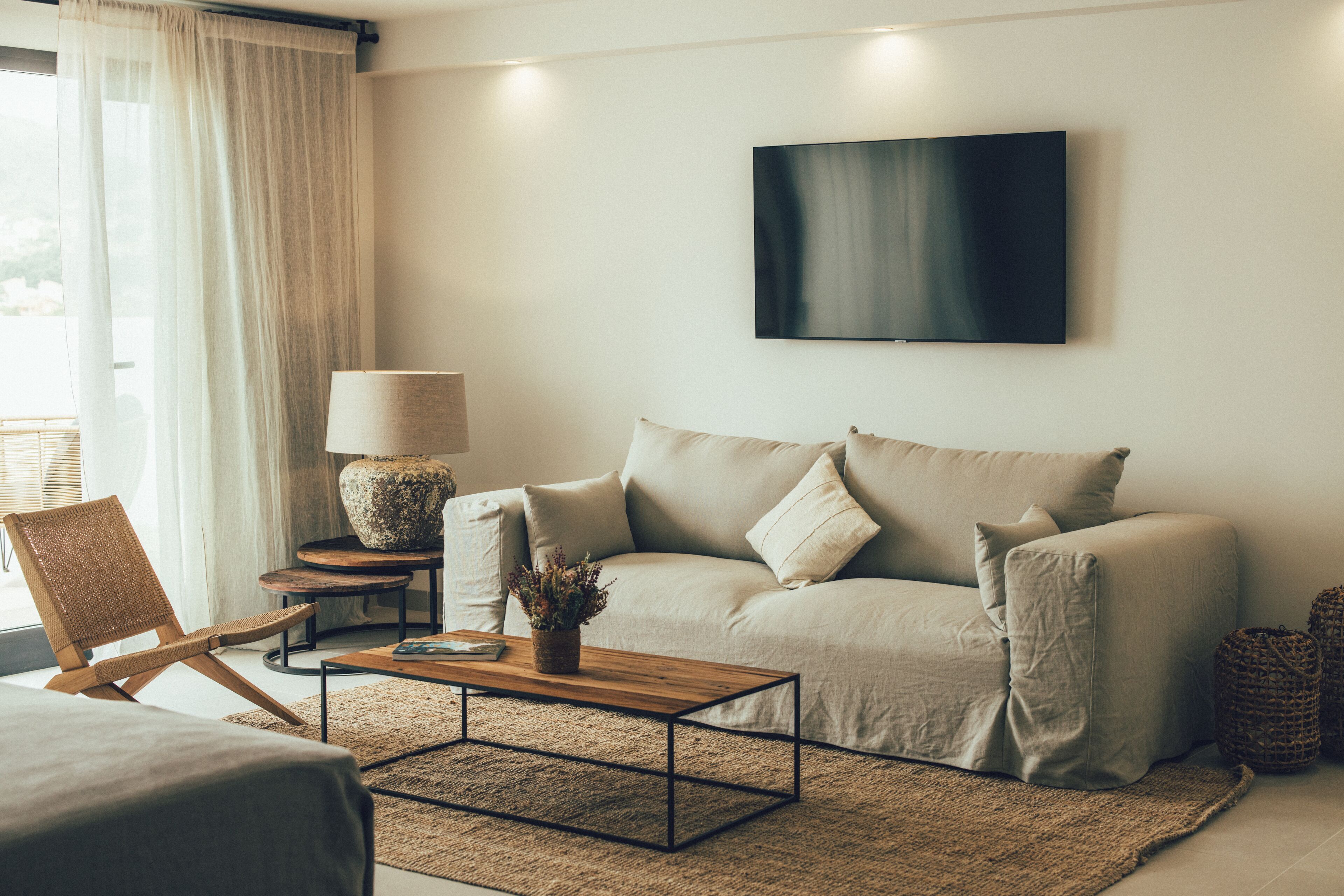 Een moderne woonkamer met een bank, een salontafel, een lamp en een televisie aan de muur.