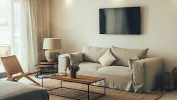 Een moderne woonkamer met een bank, een salontafel, een lamp en een televisie aan de muur.