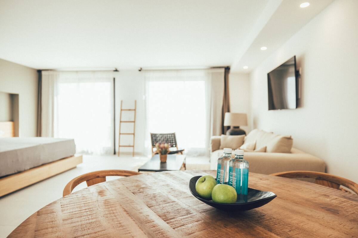 Ein modernes Wohnzimmer mit einem Holzesstisch, einer Couch und einem an der Wand befestigten Fernseher.