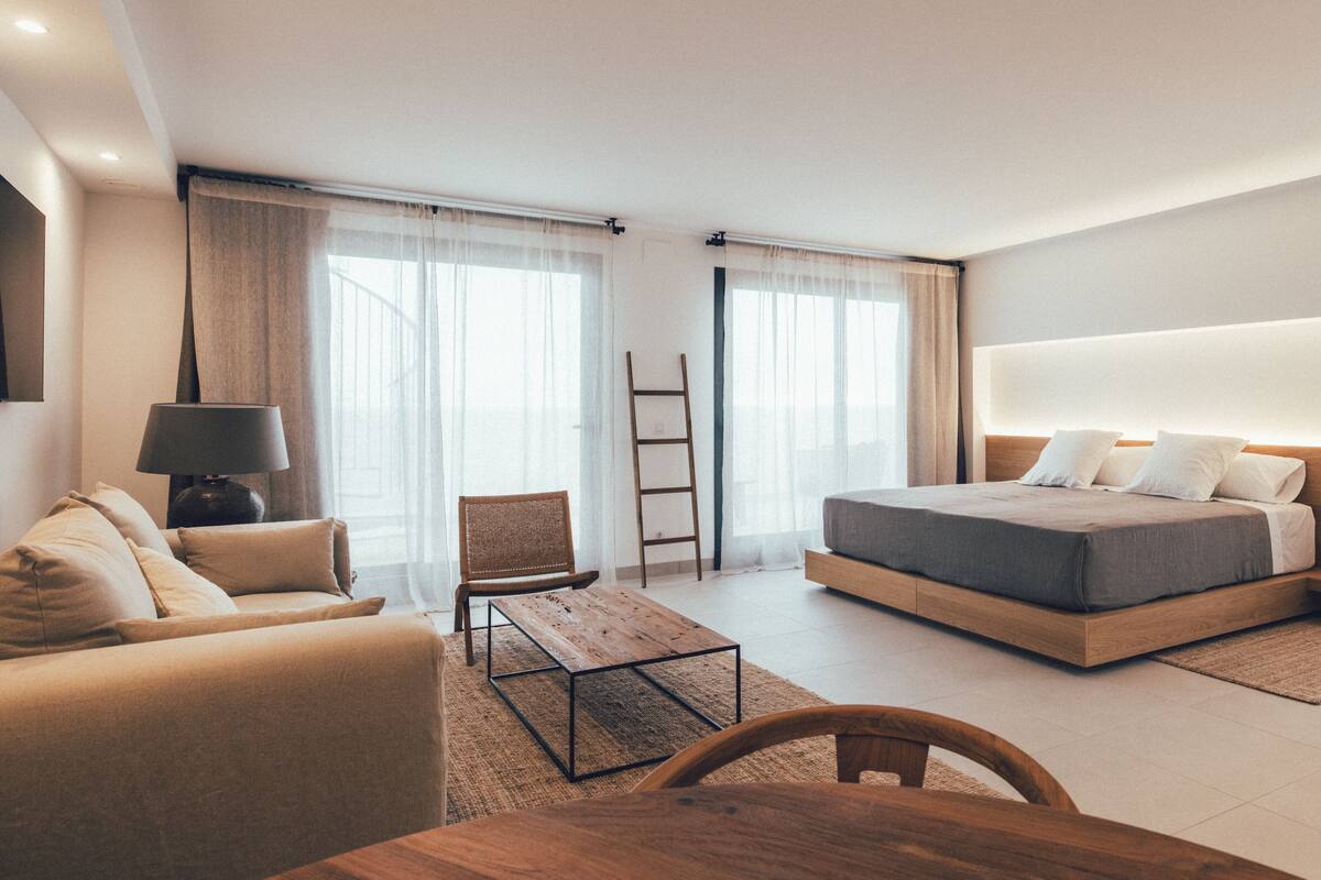 Ein modernes Schlafzimmer mit einem Bett, einem Sofa, einem Tisch und einem Stuhl.