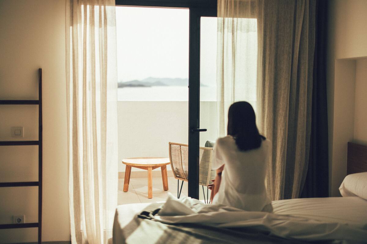 Ein Hotelzimmer mit einem Bett, einem Sessel und Blick ins Freie.