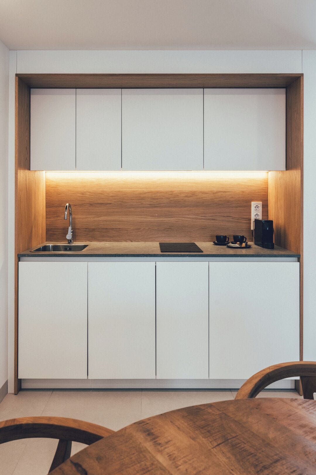 Una cocina moderna con armarios blancos, encimera de madera y un lavabo empotrado.
