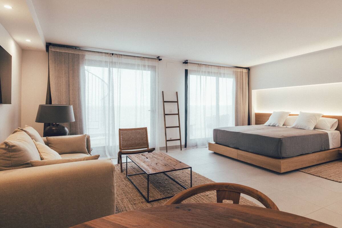Ein modernes Hotelzimmer mit Bett, Sofa, Tisch und Stuhl.