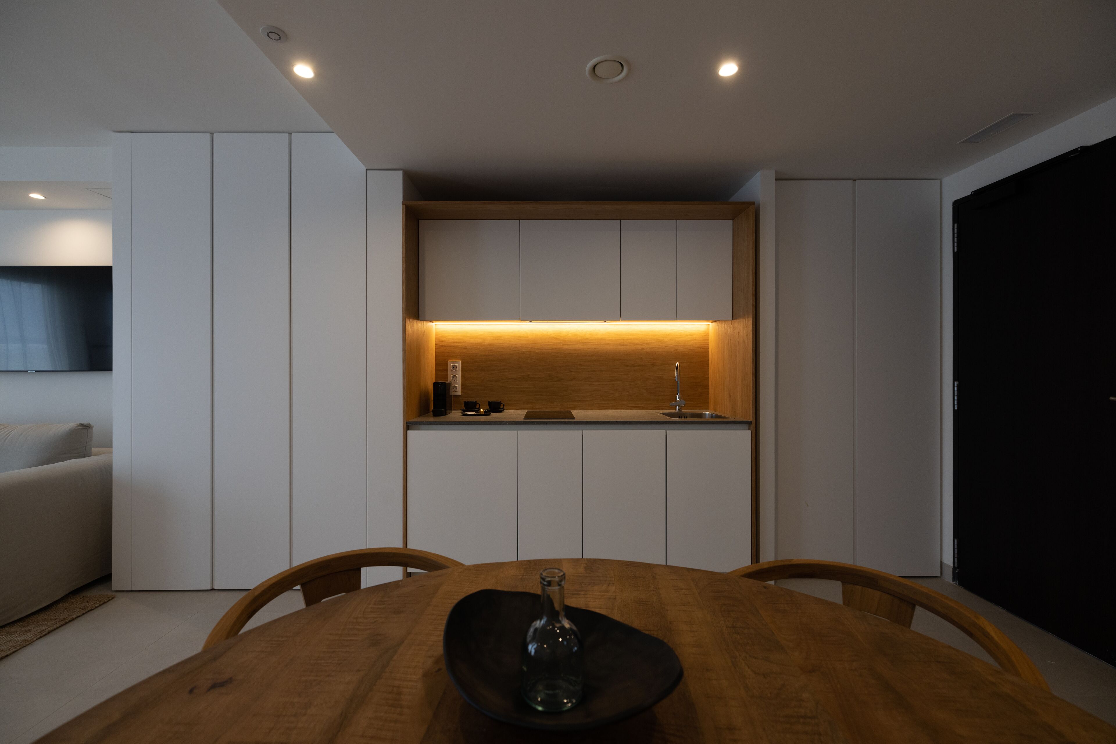 A modern kitchen with white cabinetry, a wooden countertop, and recessed lighting.