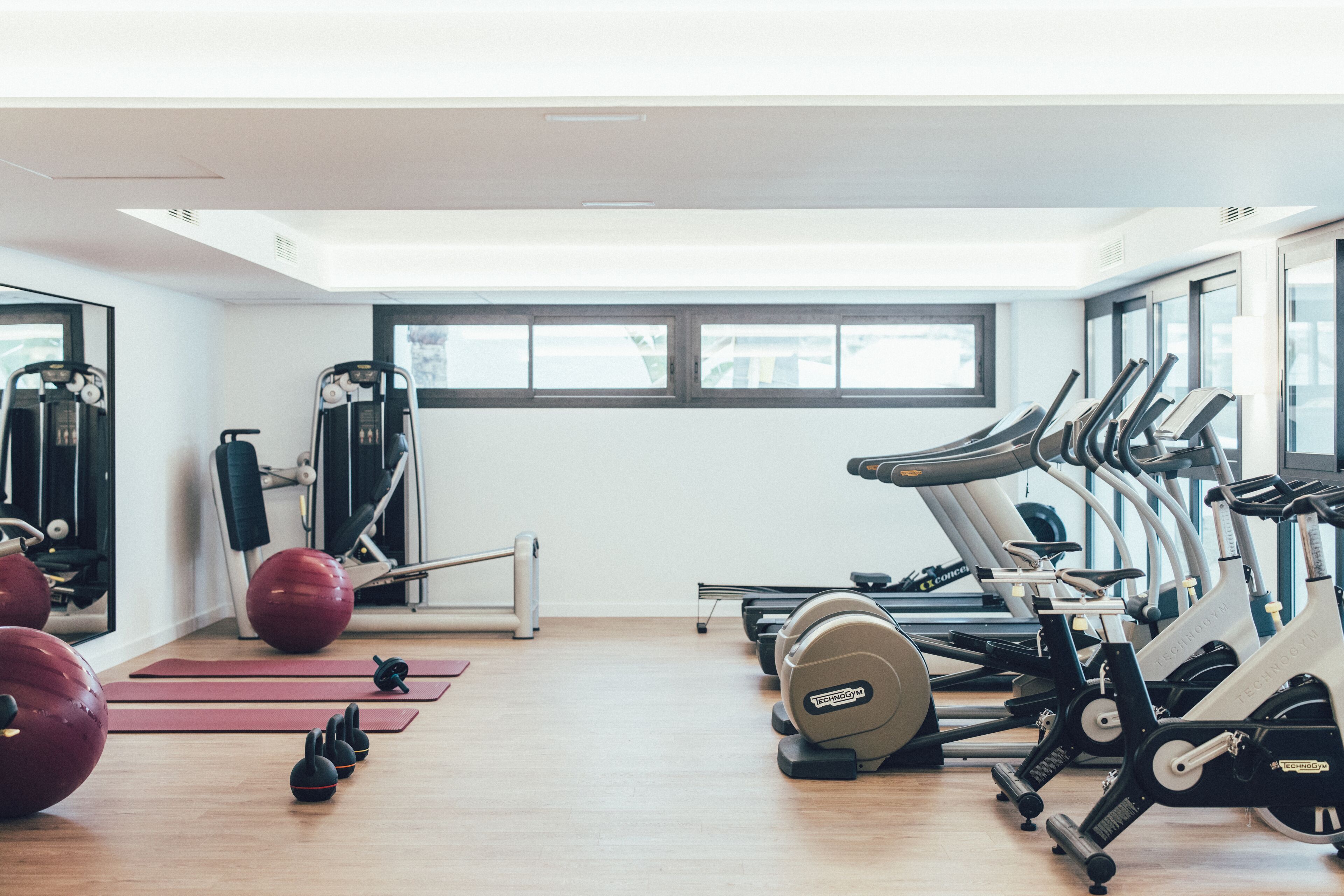 A gym with exercise equipment, a mirror, and a window.