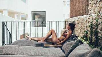 A person lying on a grey sofa with a metal railing behind them.