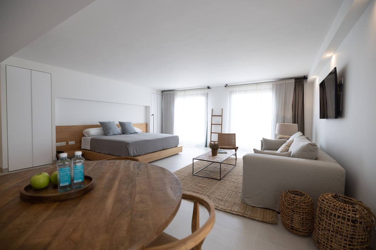 Ein modernes, helles Schlafzimmer mit einem Bett, Nachttisch und einem großen Fenster.