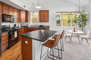 A modern kitchen with wooden cabinets, a central island, and bar stools.