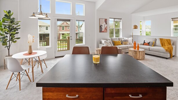 Ein modernes Wohnzimmer mit Essbereich, großen Fenstern und Blick auf die Nachbarschaft.