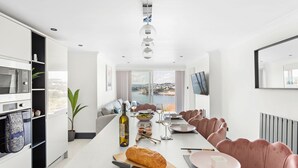 Een moderne keuken met een eethoek, een groot raam met uitzicht en een aan de muur bevestigde televisie.