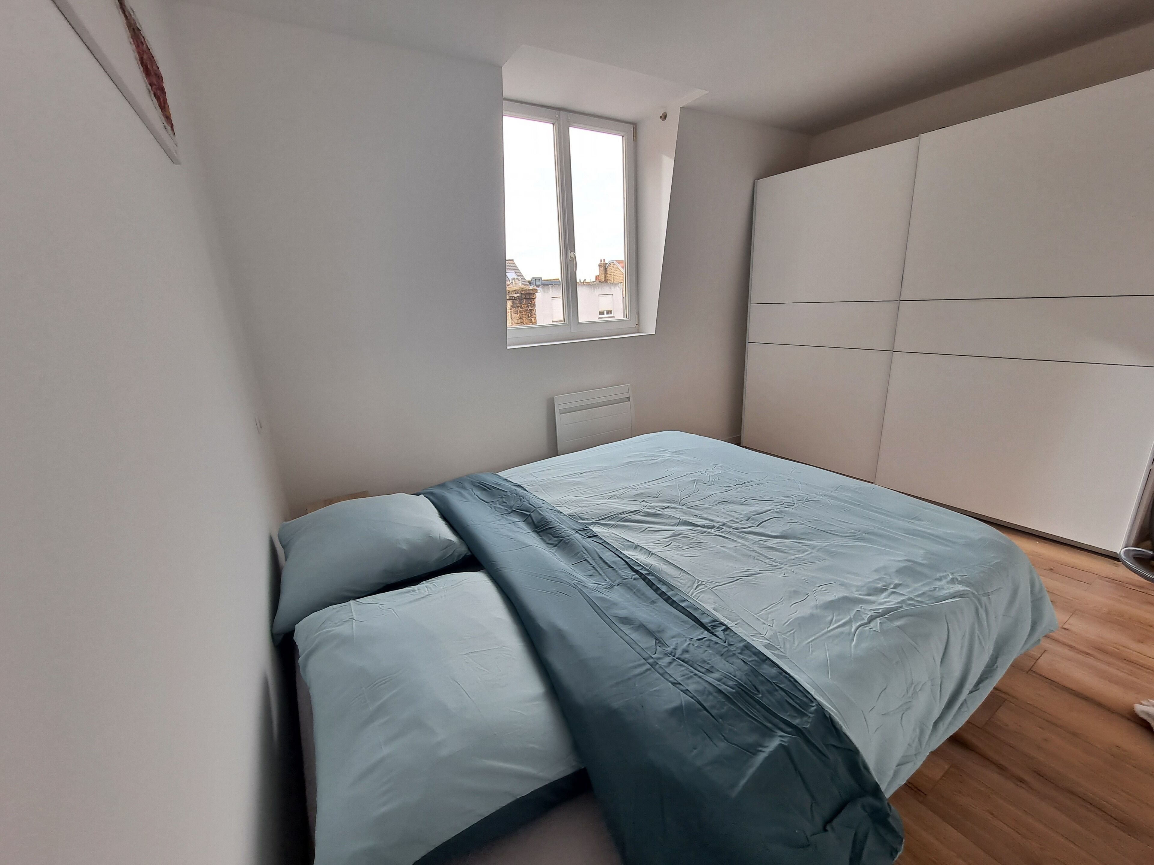 Un dormitorio con cama, ventana y armario.