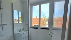 A modern bathroom with a glass shower enclosure, a white sink, and a large mirror.