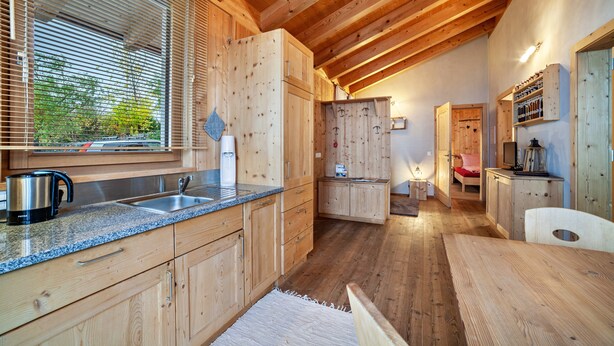 Een houten interieur met een keuken, een eetgedeelte en een slaapkamer met een bed en een televisie.