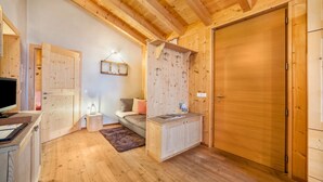 Un interior de madera con un sofá, una mesita, un armario y una puerta.