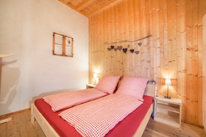 Una habitación con paneles de madera, una cama, dos mesitas de noche y un adorno en la pared.