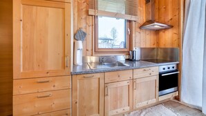 Una cocina de madera con ventana, estufa y lavamanos.