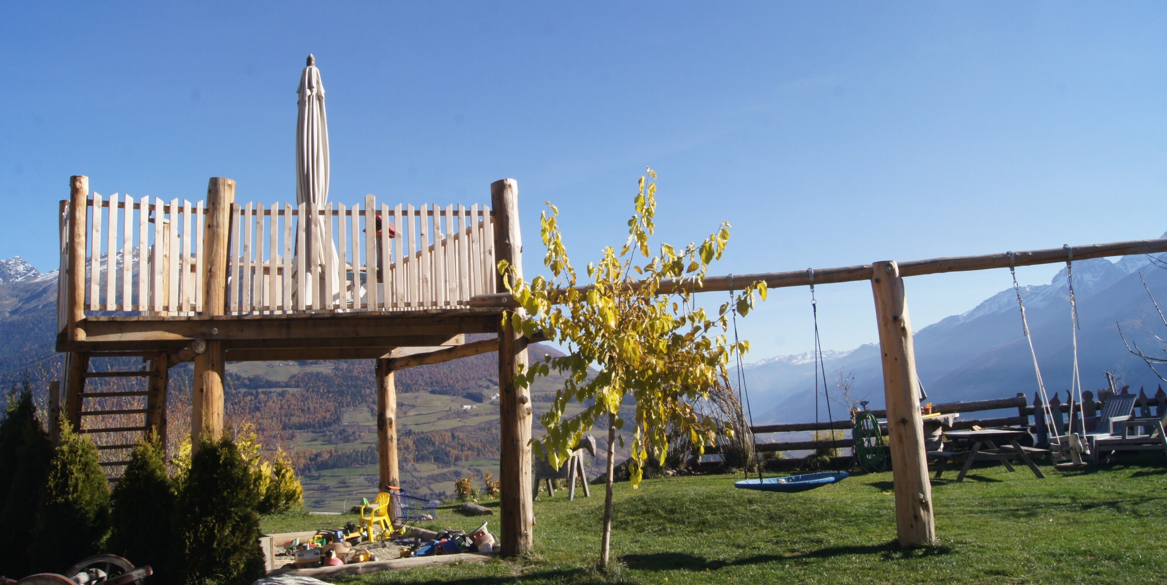 Una terraza de madera con una hamaca, una mesa de picnic y vistas a montañas.