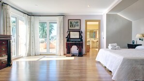 Um quarto espaçoso com uma cama grande, um piano e vista para o exterior.