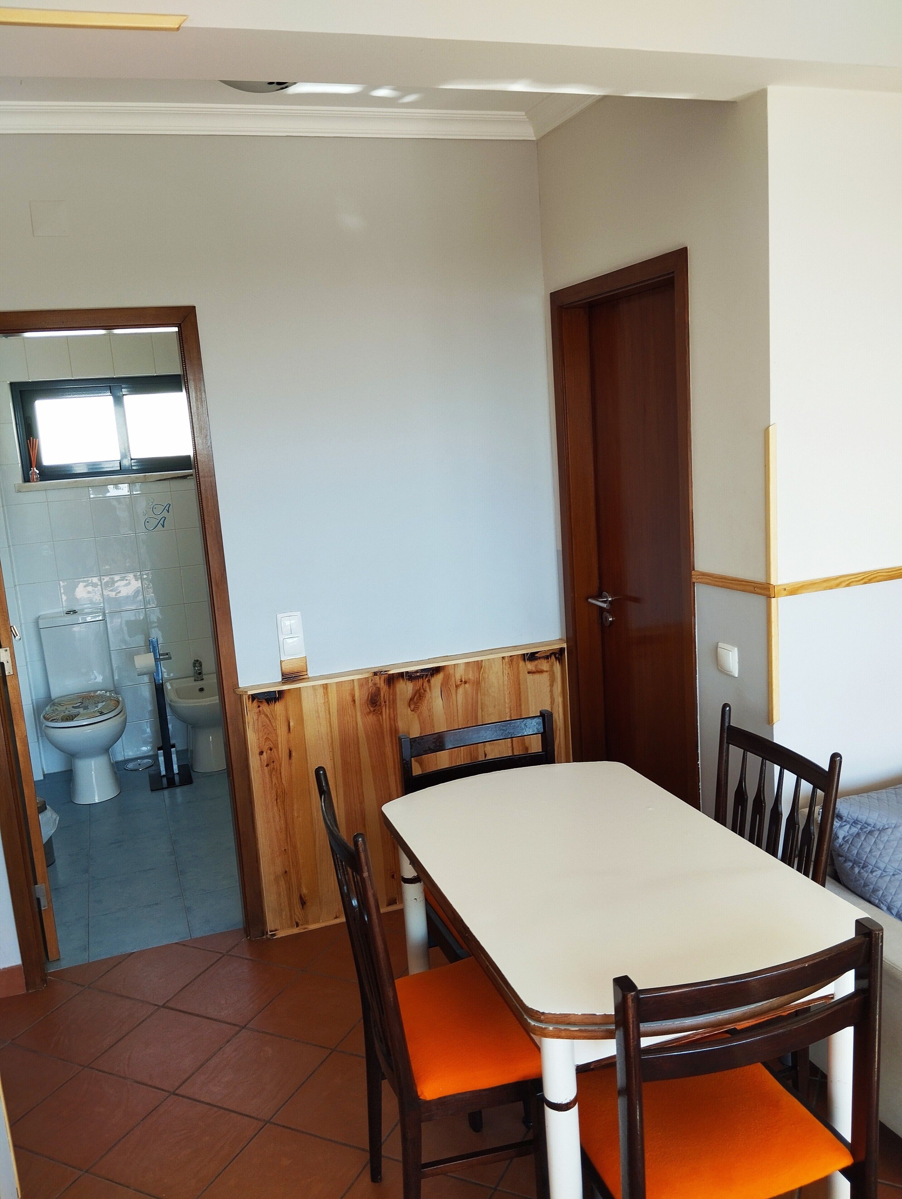A dining area with a table and chairs, a wooden partition, and a view into the kitchen.