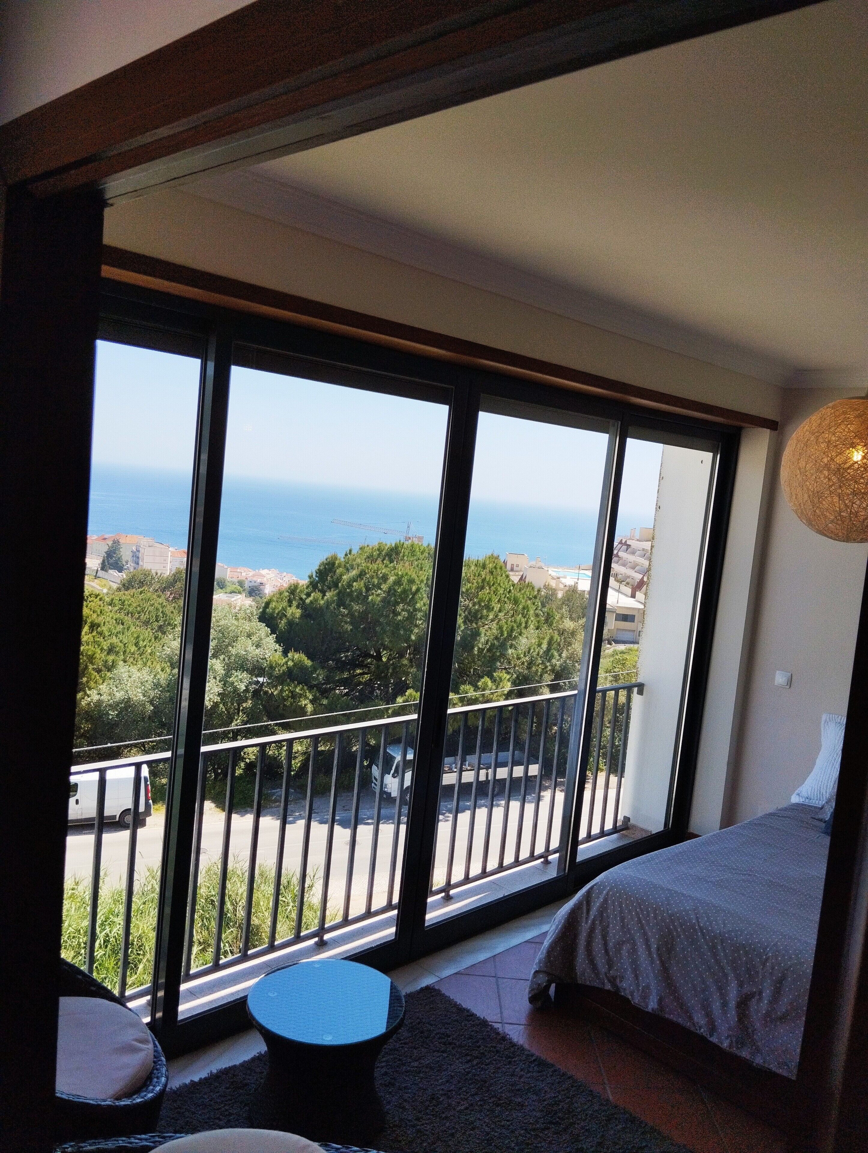 A bedroom with a large window, a bed, and a small table.