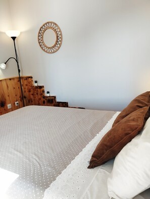 A bed with a white and brown pillow, a wooden headboard, a wall-mounted mirror, and a floor lamp. - Holiday Apartment 'Casa Vale do Paraíso' with Sea View, Private Balcony & Wi-Fi (Sesimbra)