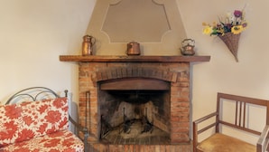 A fireplace with a brick surround, a wooden mantel, and a wall-mounted flower arrangement. - Agriturismo "Universal Harmony - Pettirosso" with Mountain View and Shared Pool (Dicomano)