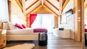 A wooden interior with a bed, a suitcase, and a TV on the wall.