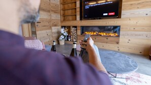 A person sitting on a couch with a television and fireplace in a wooden room.