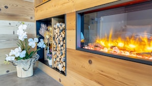 A modern interior with a wooden wall, a glass fireplace, and a decorative plant arrangement.