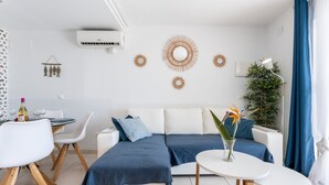 A modern living room with a sectional sofa, a dining table with chairs, a small side table, and decorative wall art.